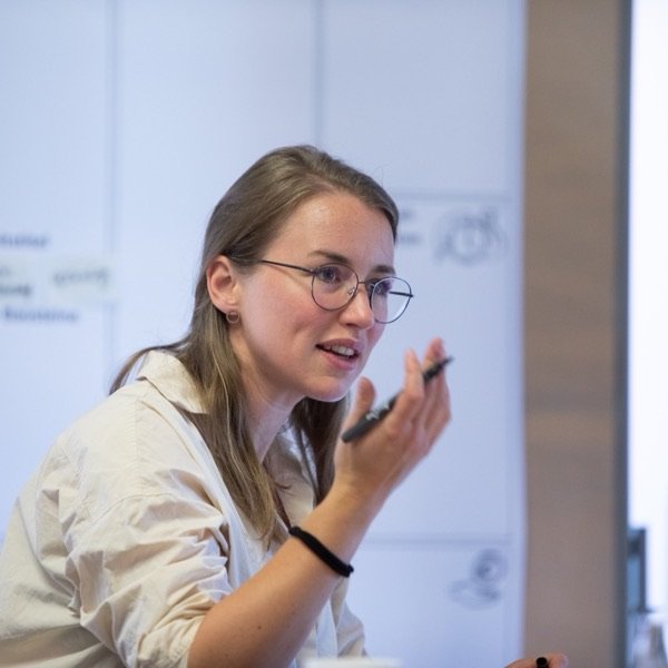 Lia Weitz im Gespräch während eines Workshops, im Hintergrund eine beschriftete Pinnwand