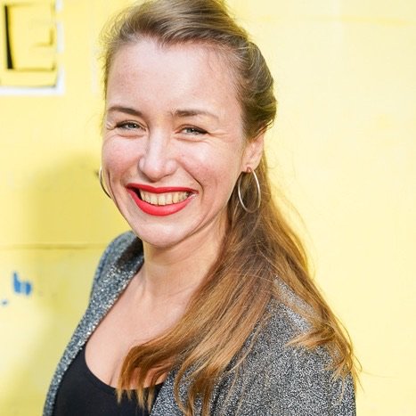 Lia Weitz lachend vor einer gelben Wand